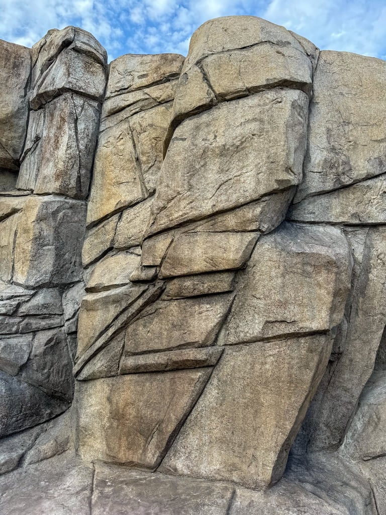 Large stacked granite boulders with natural fissures against a blue sky