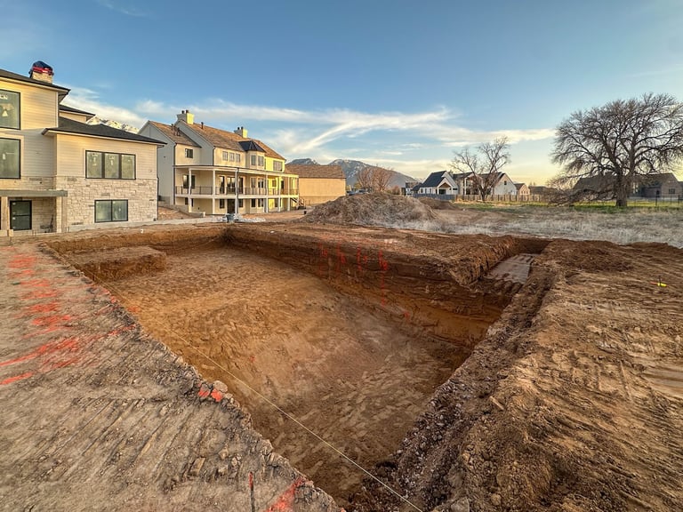 Residential construction site with excavated foundation pit and newly built homes in suburban neighborhood