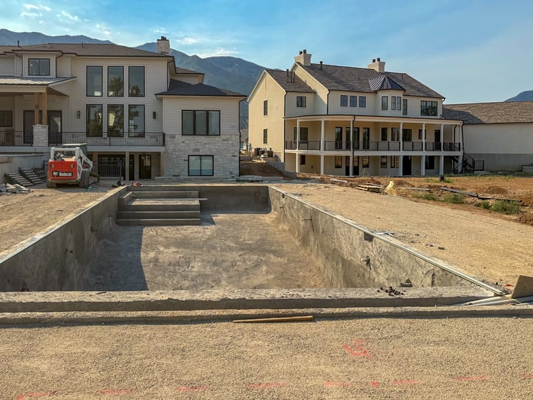 Residential neighborhood showing newly constructed pool foundation with surrounding homes and mountains in background