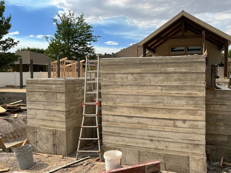 Construction site with wooden garden shed structure, metal ladder, and concrete foundation under blue sky
