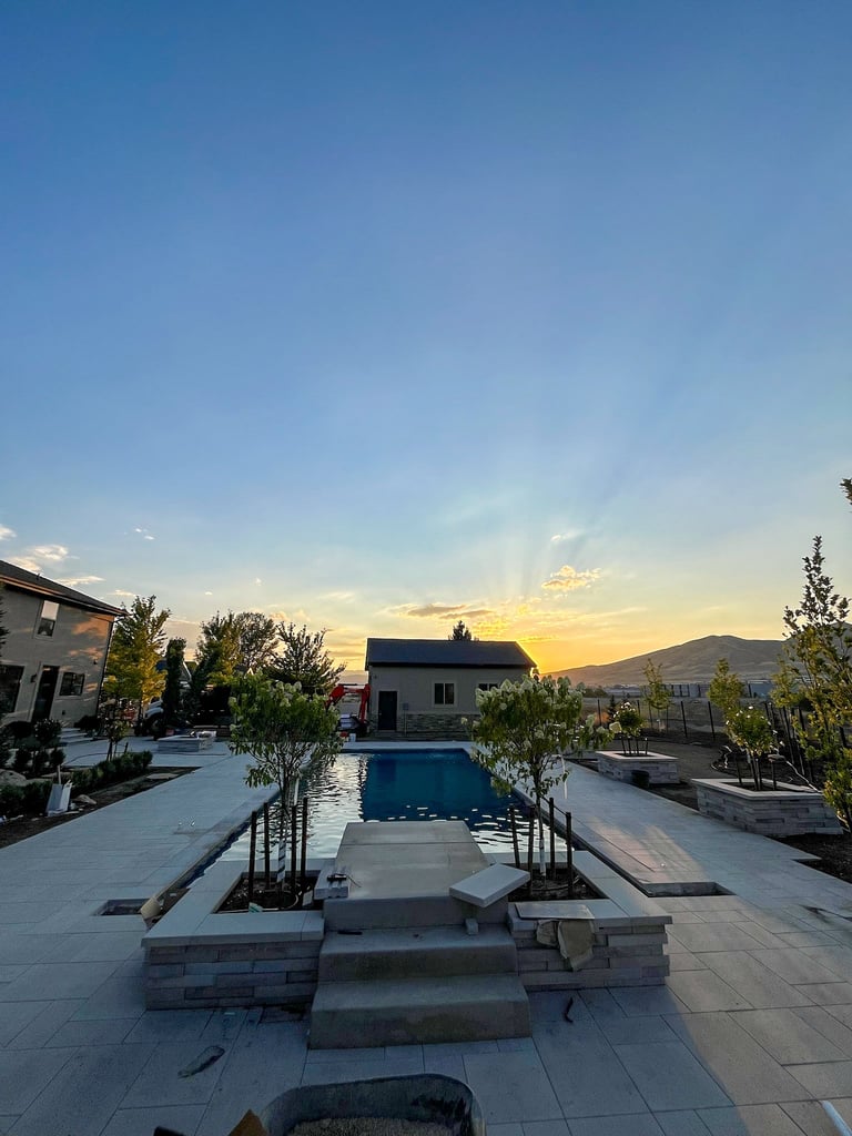 Luxury backyard with rectangular swimming pool at sunset, flanked by contemporary homes and mountains in background